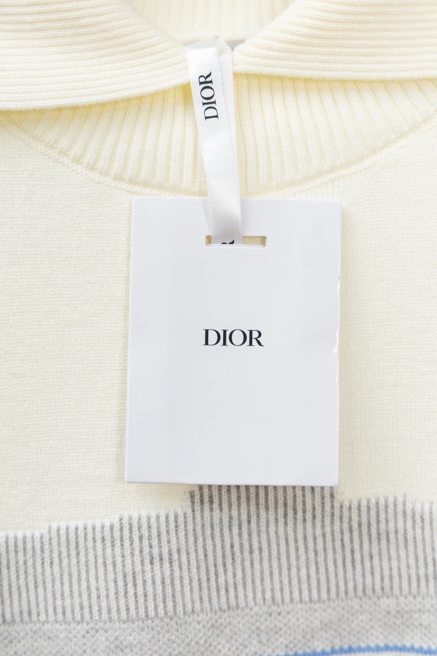 Cream sweater collar with white Dior tag attached to neckline