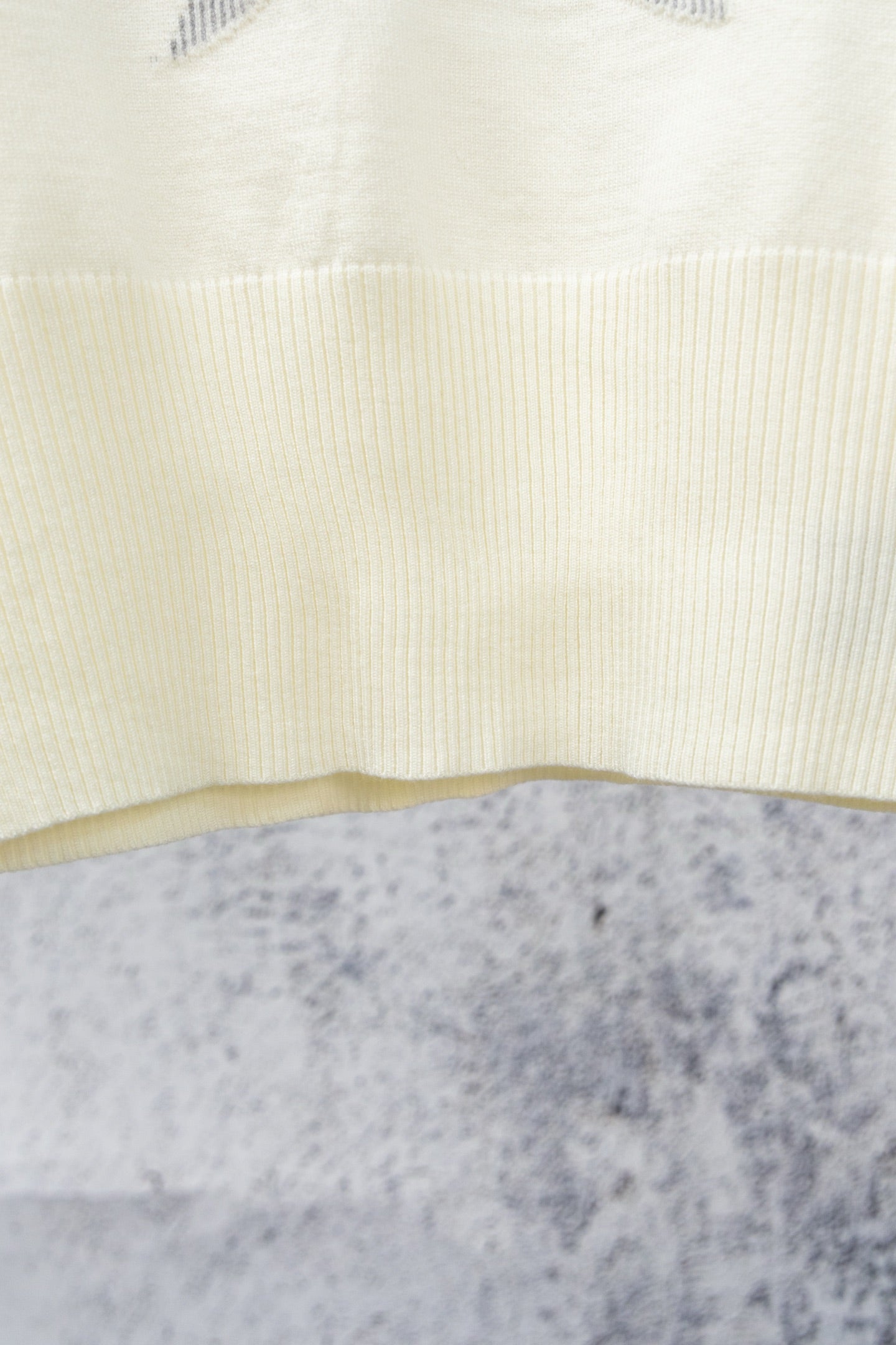 Cream ribbed sweater chest panel with subtle texture and curved knit detail