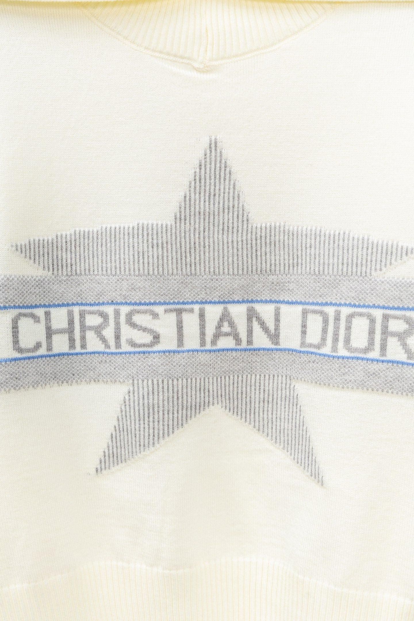 Cream sweater with gray star graphic and blue stripe band reading CHRISTIAN DIOR