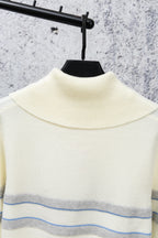 Cream sweater with high ribbed turtleneck and blue stripe band across chest