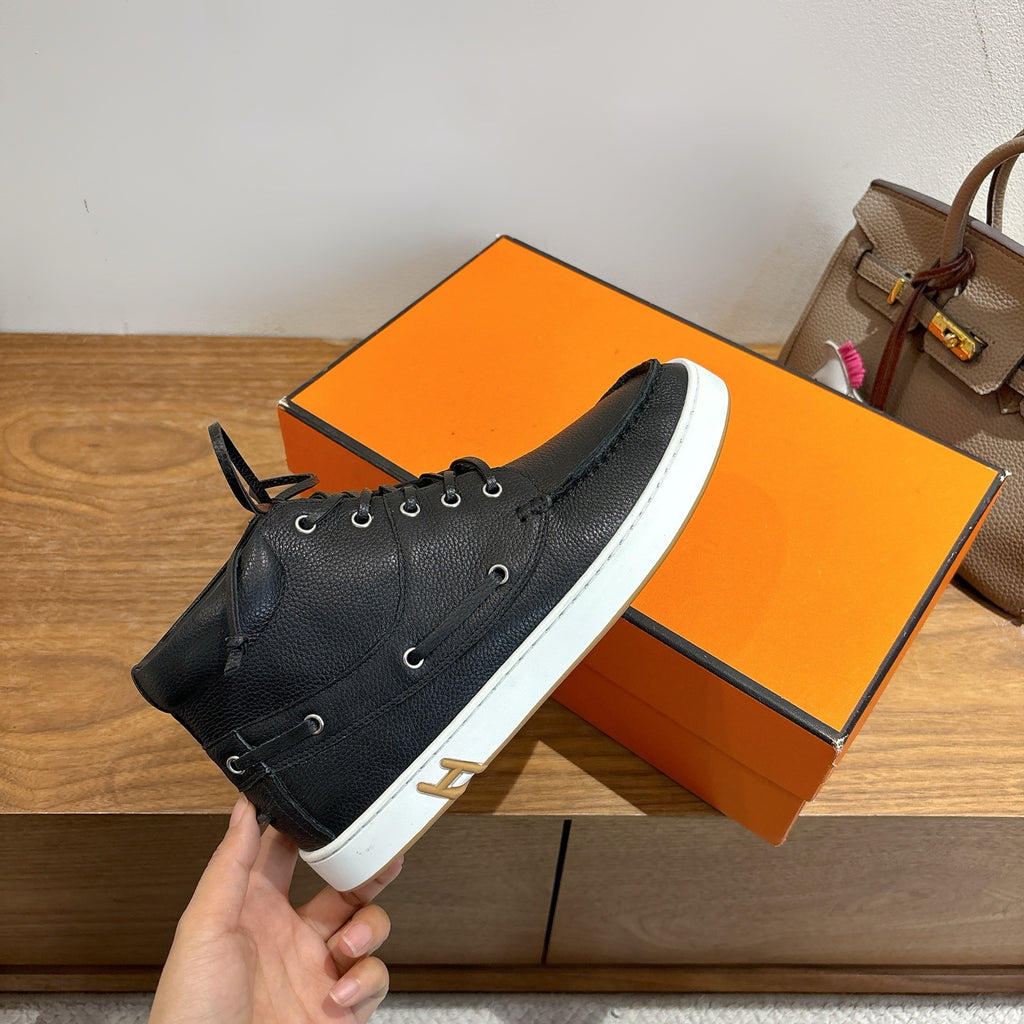 Hermes black lace-up sneaker held in hand on orange shoebox, white sole
