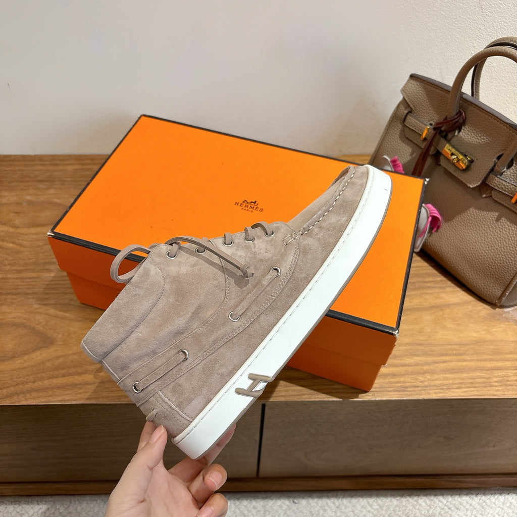Hermes unisex gray suede high-top sneakers held in hand, lace-up and white sole.