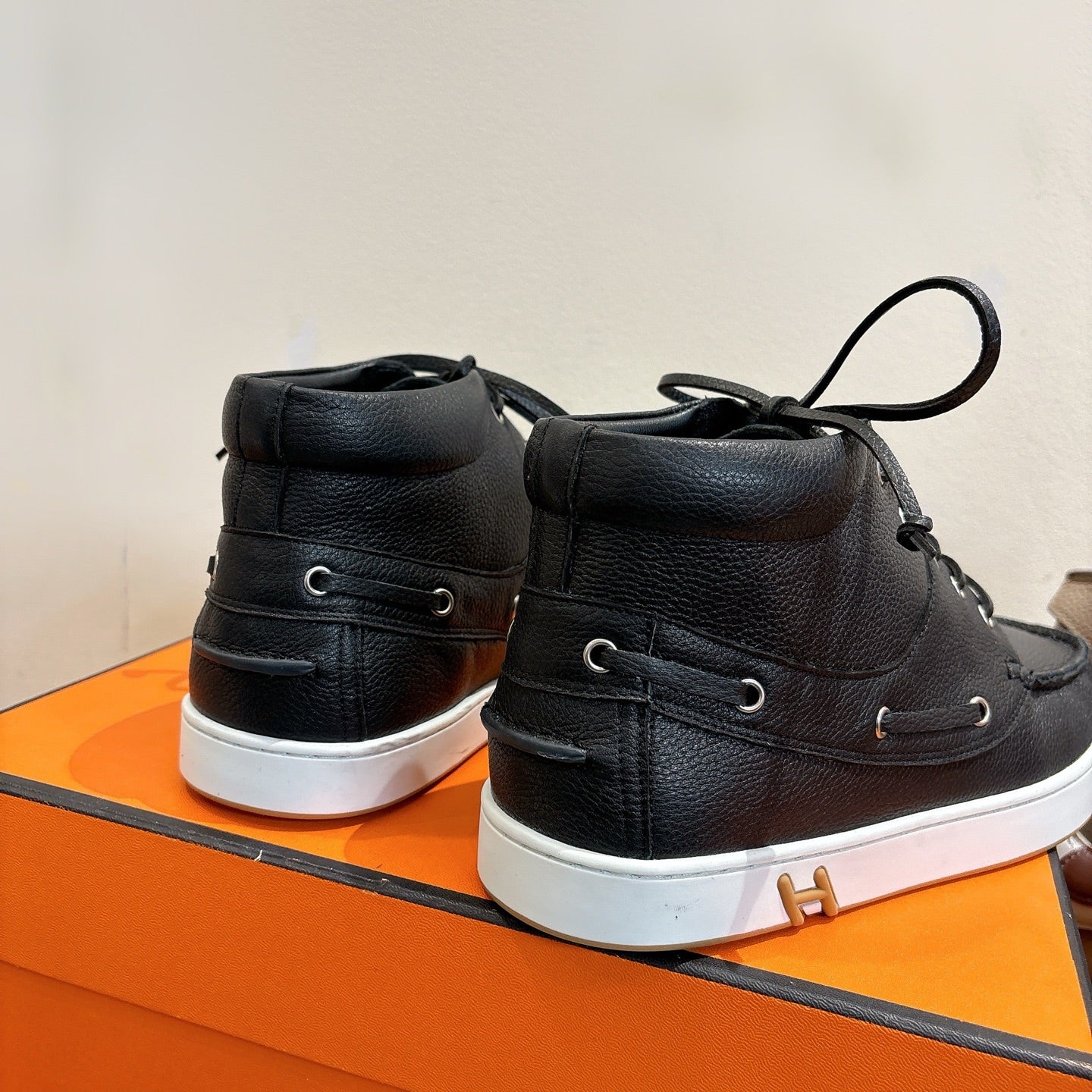 Hermes black high-top sneakers back view, cushioned heel and white rubber sole