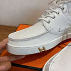 White sneaker front with lace-up top, white rubber sole and gold H logo