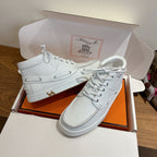 White high-top sneakers with lace-up closure, gold H emblem on side