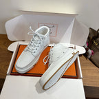 White lace-up sneakers on open box, leather upper with gold H side emblem