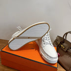 White sneakers with outsole view, textured tread and gold-edged side
