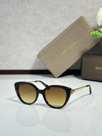 Black oversized round sunglasses with warm yellow lenses and gold-tone hinges