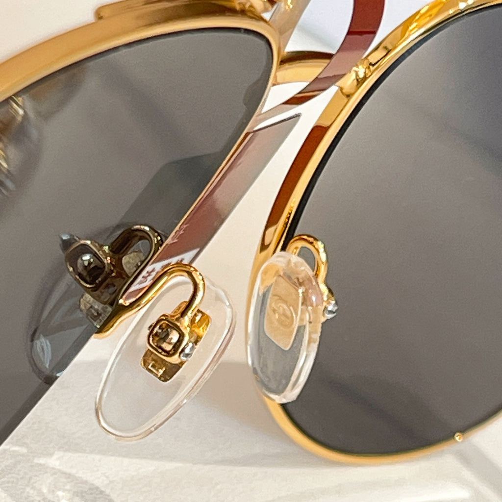Gucci glasses close-up: gold-tone frame detail and dark lenses with decorative temple accents