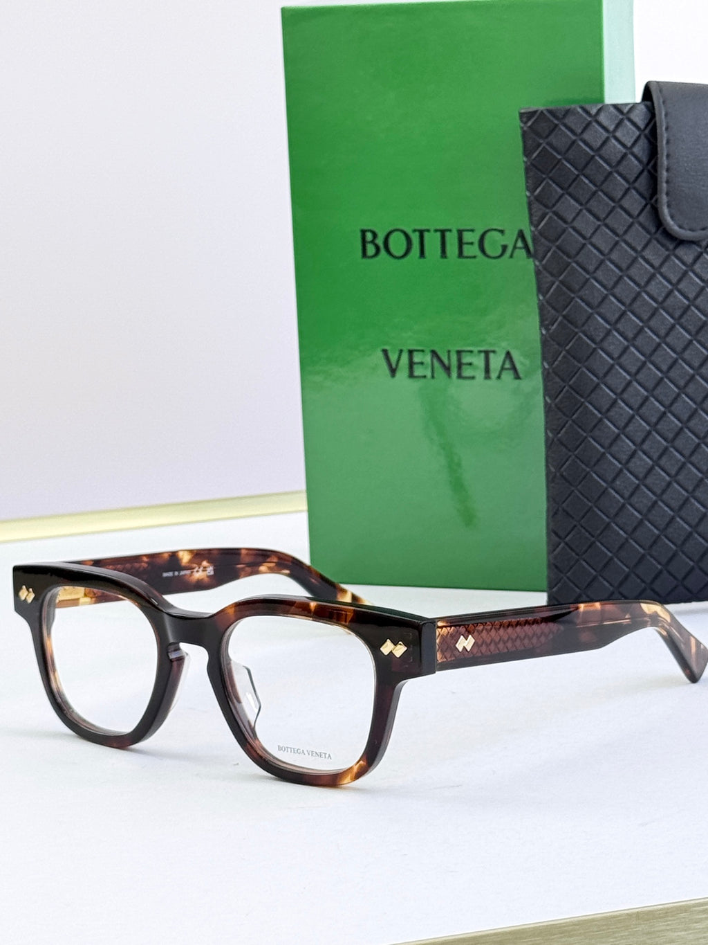 Bottega Veneta eyeglasses with tortoiseshell frames and gold textured temples.