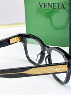 Bottega Veneta eyeglasses with black frames, gold patterned bridge and temples.