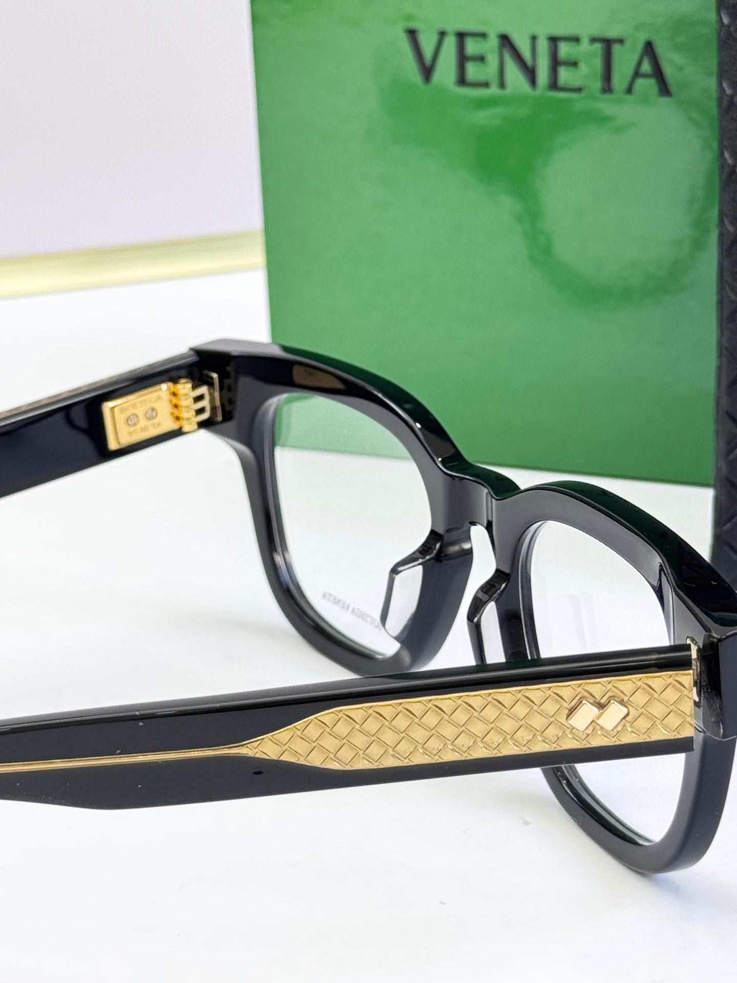 Bottega Veneta eyeglasses with black frames, gold patterned bridge and temples.