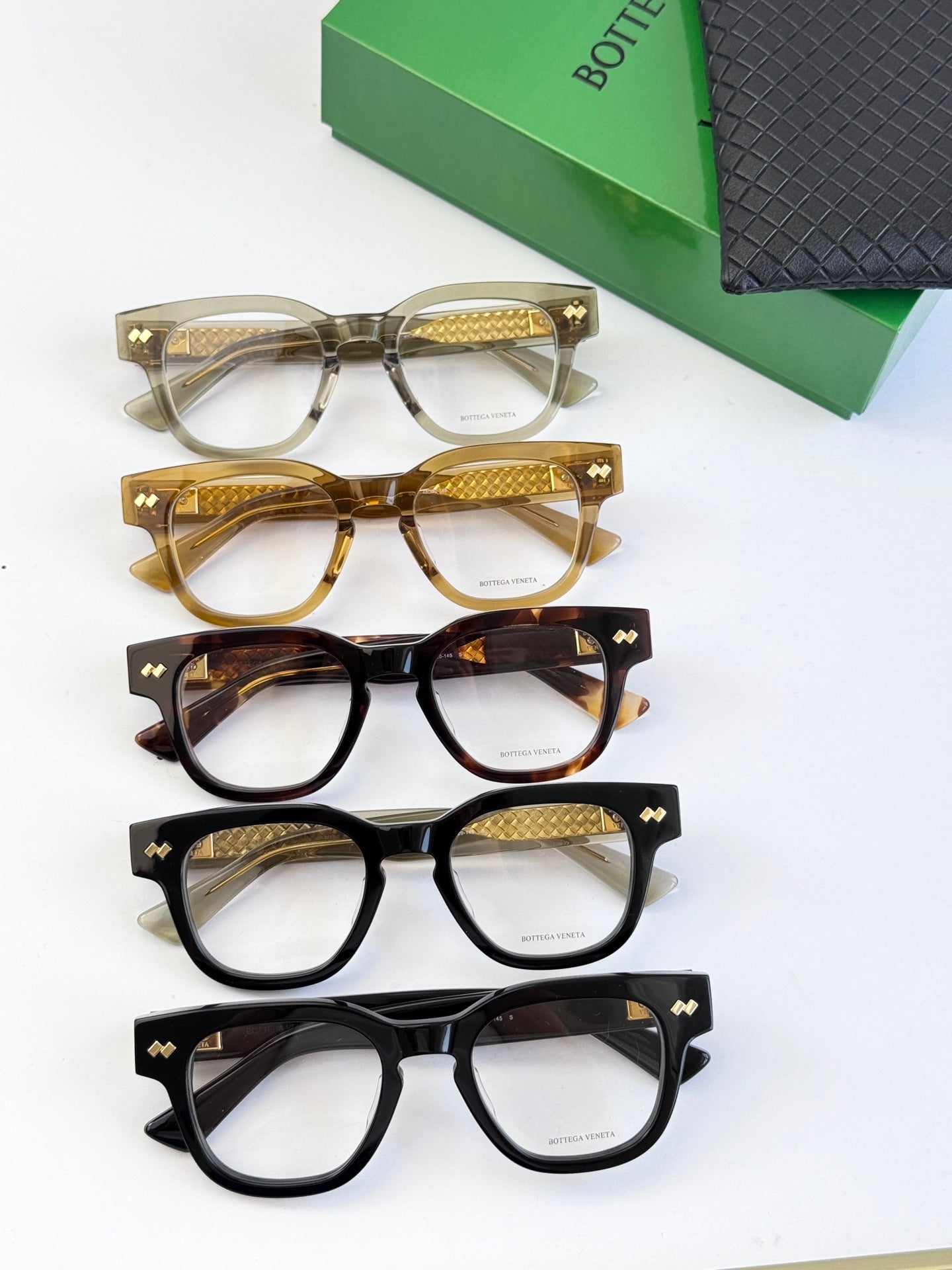 Set of Bottega Veneta eyeglasses in assorted frame colors with gold textured temples.