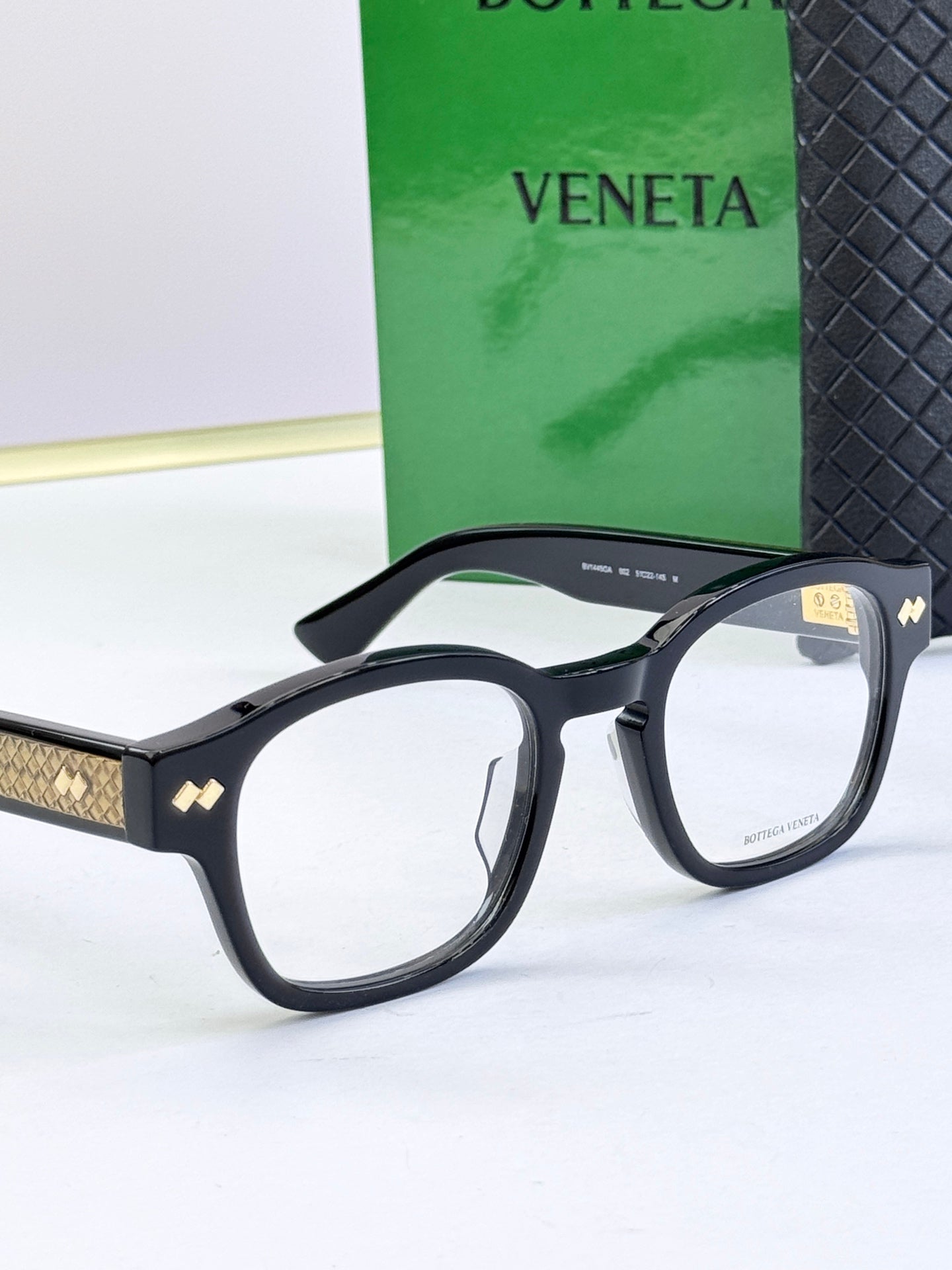 Close-up of black round eyeglasses with gold patterned temple accents