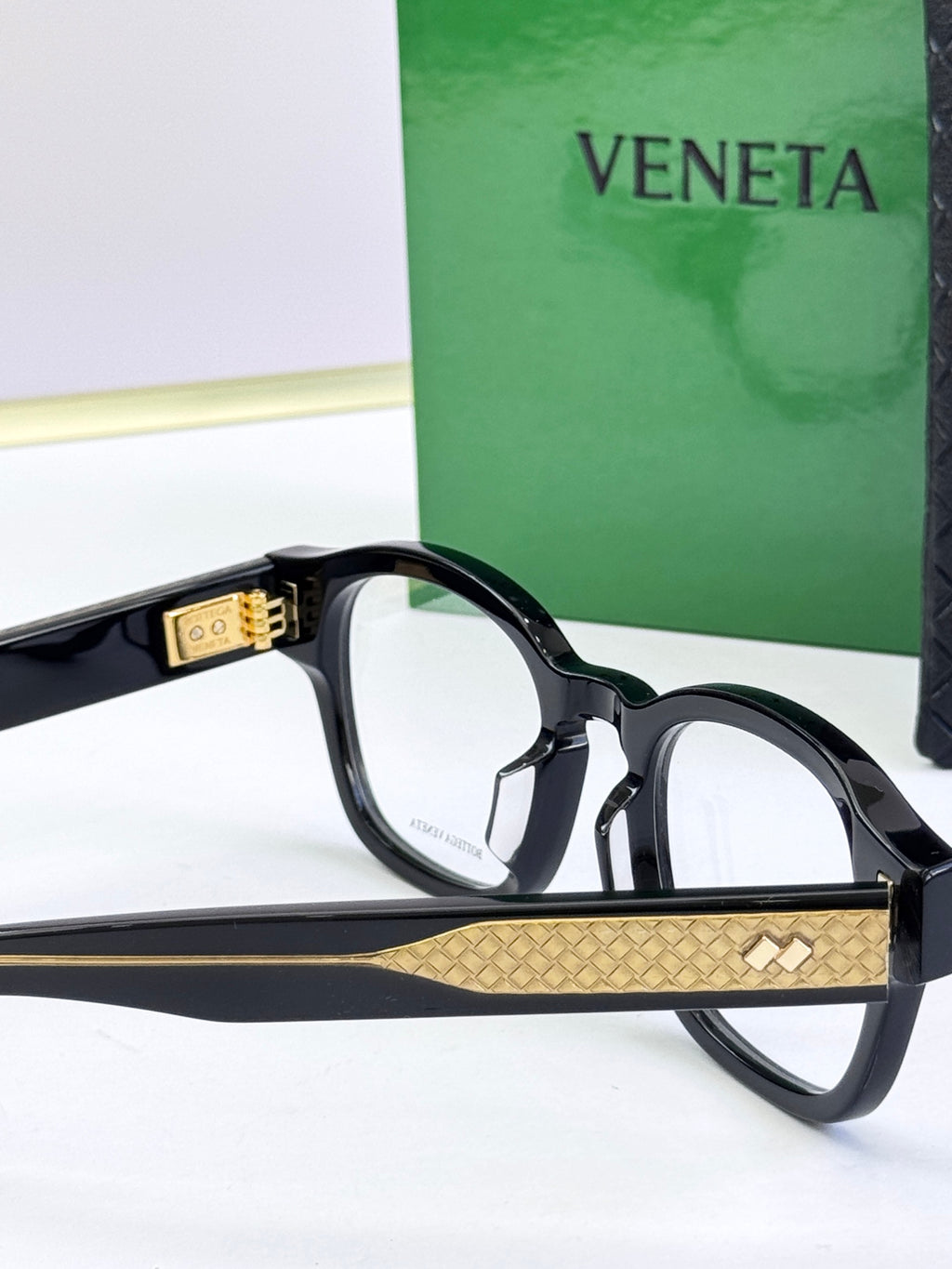 Side view of black round eyeglasses with gold patterned temple band