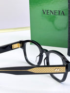 Side view of black round eyeglasses with gold patterned temple band