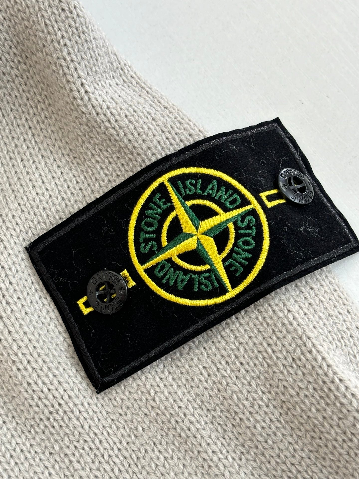 Stone Island logo patch on light gray knit sweater fabric