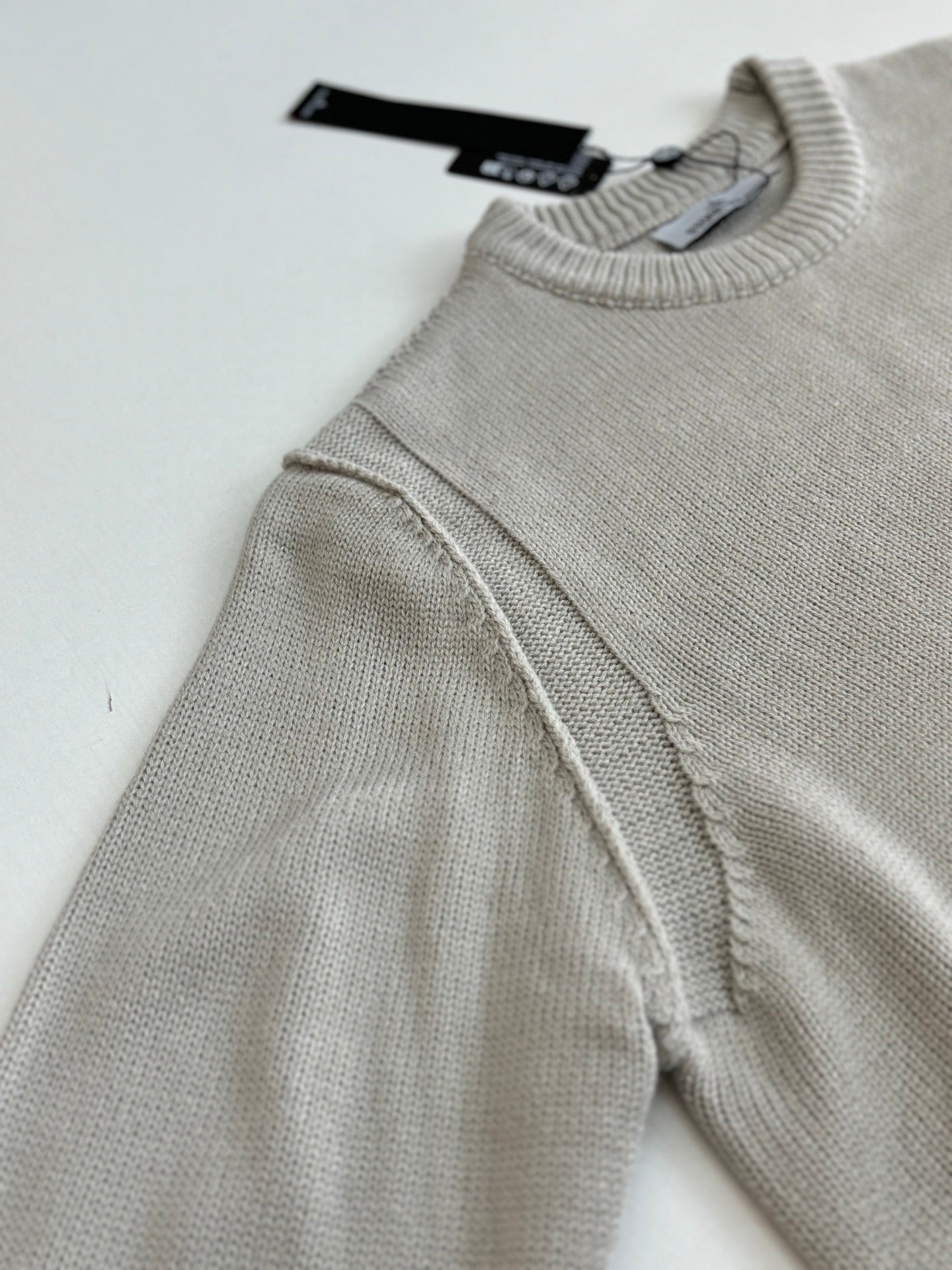 Light gray knit sweater sleeve with shoulder seam and ribbed neckline