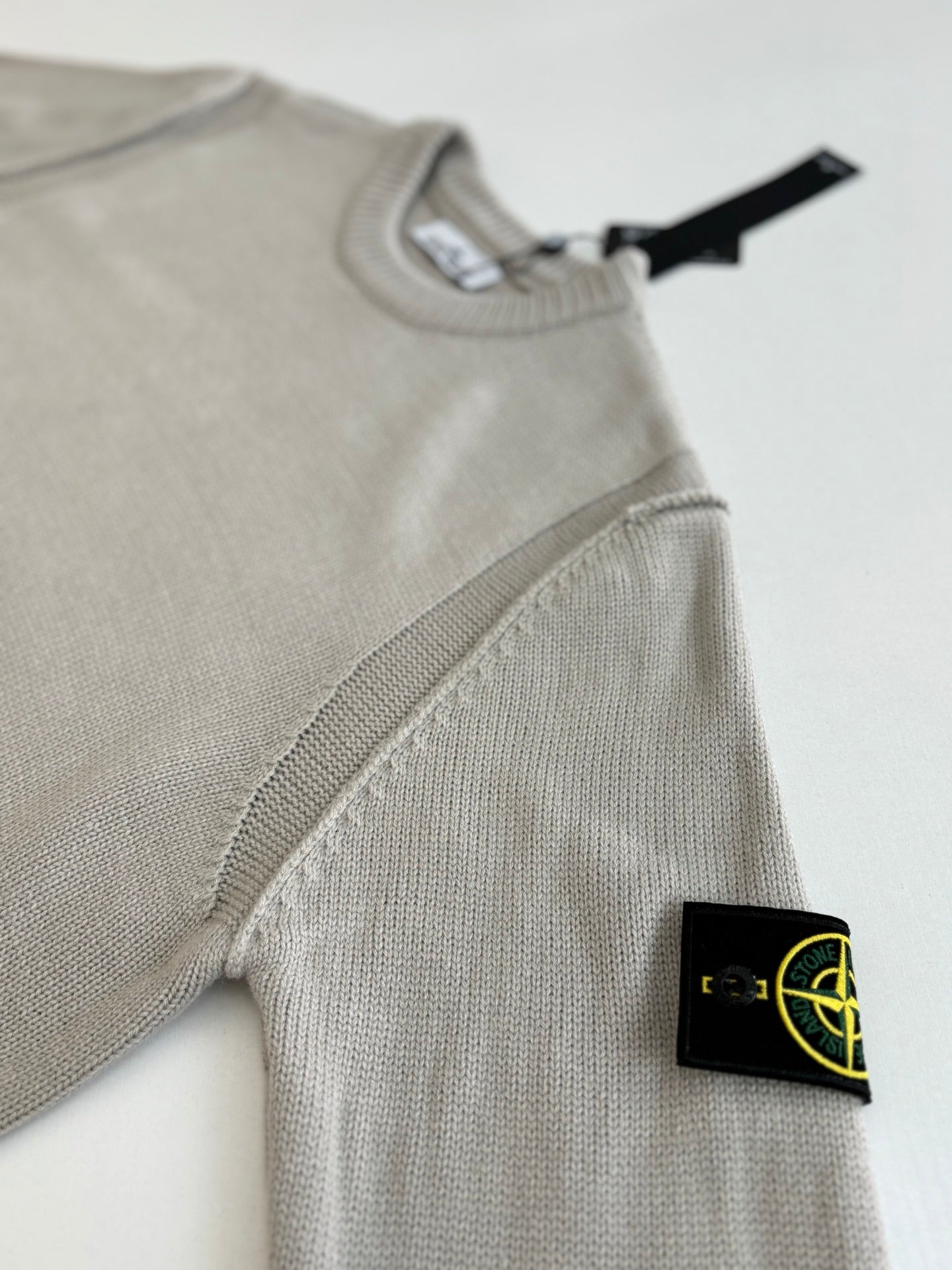 Light gray knit sweater with ribbed crew neck and side logo patch