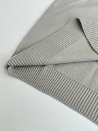 Light gray knit sweater detail: ribbed trim cuffs and folded hem