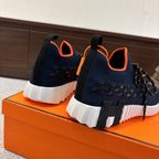 Hermes unisex navy knit sneakers with orange trim and thick white sole on display.