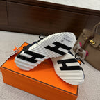 Hermes unisex sneaker outsole view: white tread sole with black detail and navy upper.