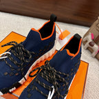 Hermes unisex sneakers in navy with orange collar trim, black laces, white cushioned sole.