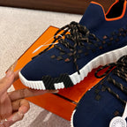 Hermes unisex sneaker close-up: navy knit upper with black laces and white sole.