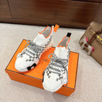 Hermes unisex sneakers, white knit with gray laces and orange trim, on orange shoebox