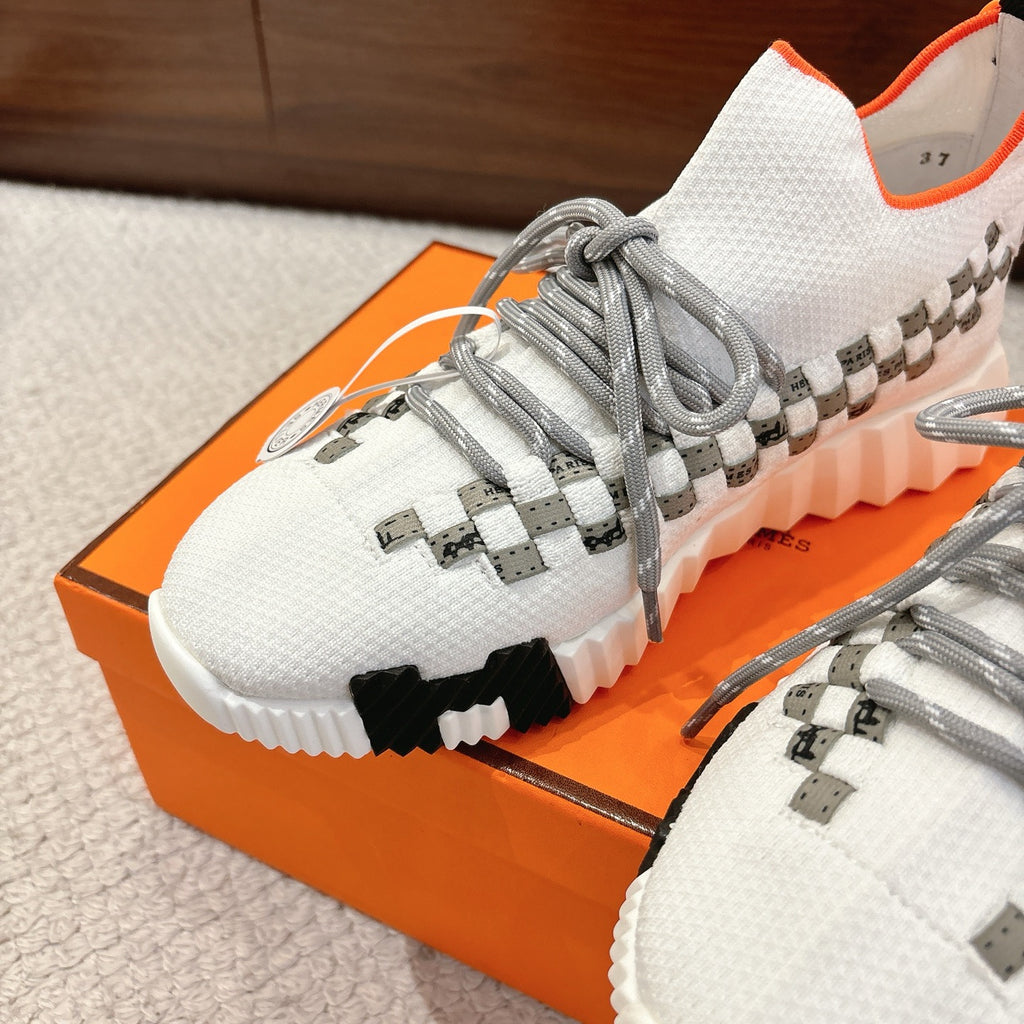 Hermes unisex sneakers close-up, white knit upper with gray laces and checkered straps