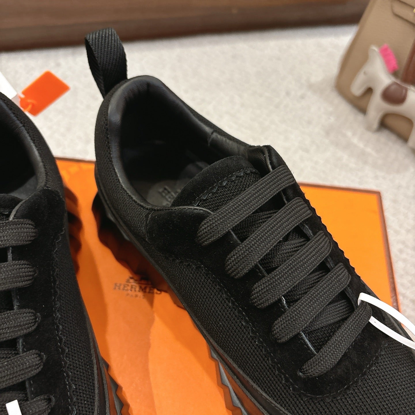 Hermes unisex black lace-up sneaker close-up with textured upper.