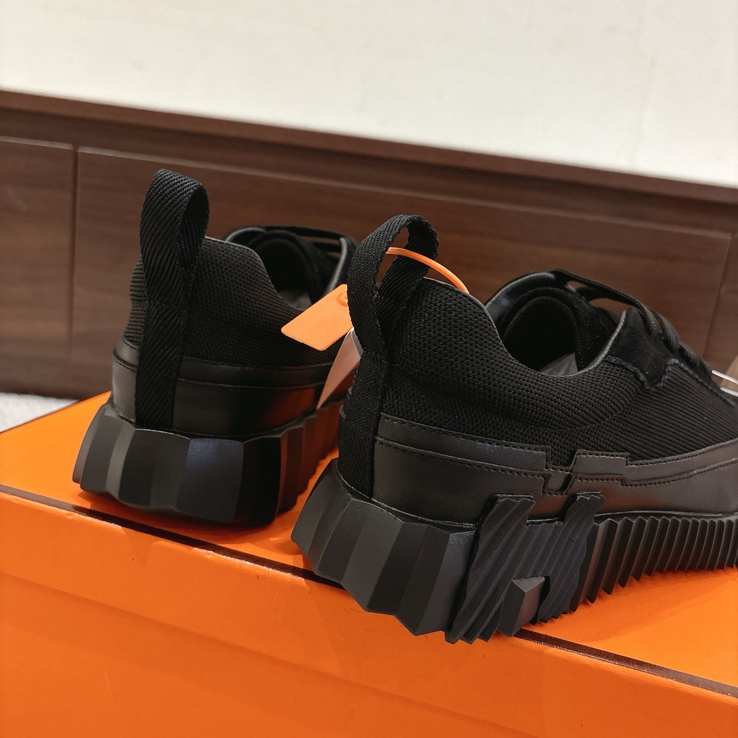 Hermes unisex black sneakers, heel and back view with stacked rubber sole.