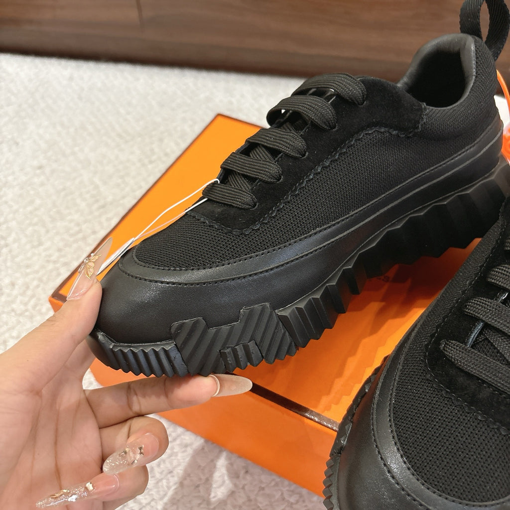 Hermes unisex black sneaker close-up, lace-up upper with ribbed outsole edge.