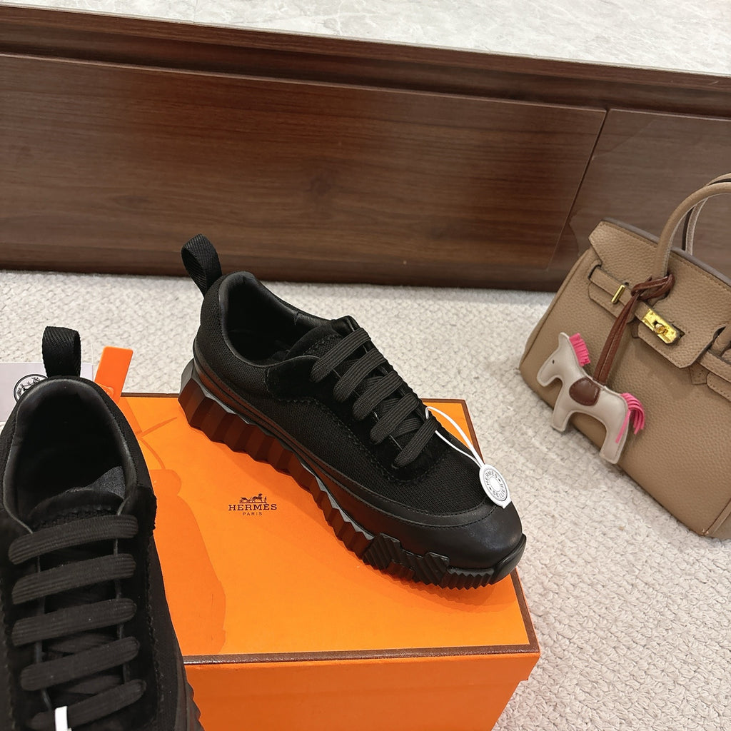Hermes unisex black sneakers with lace-up closure and chunky rubber outsole.