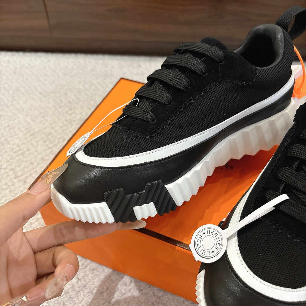 Hermes unisex black low-top sneaker close-up, white trim stripe, lace-up
