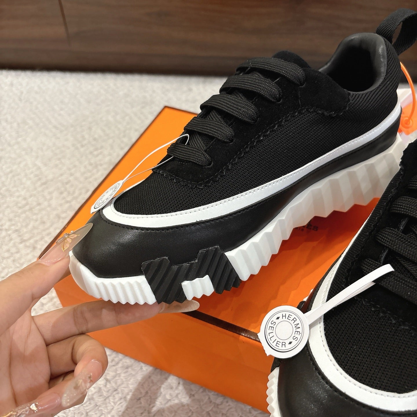 Hermes unisex black low-top sneaker close-up, white trim stripe, lace-up