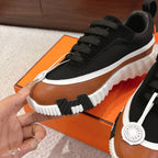 Unisex sneaker detail: black textile upper, tan overlay, white ridged sole, lace-up