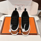 Unisex athletic sneakers in black and tan with black laces, white sole, logo badge