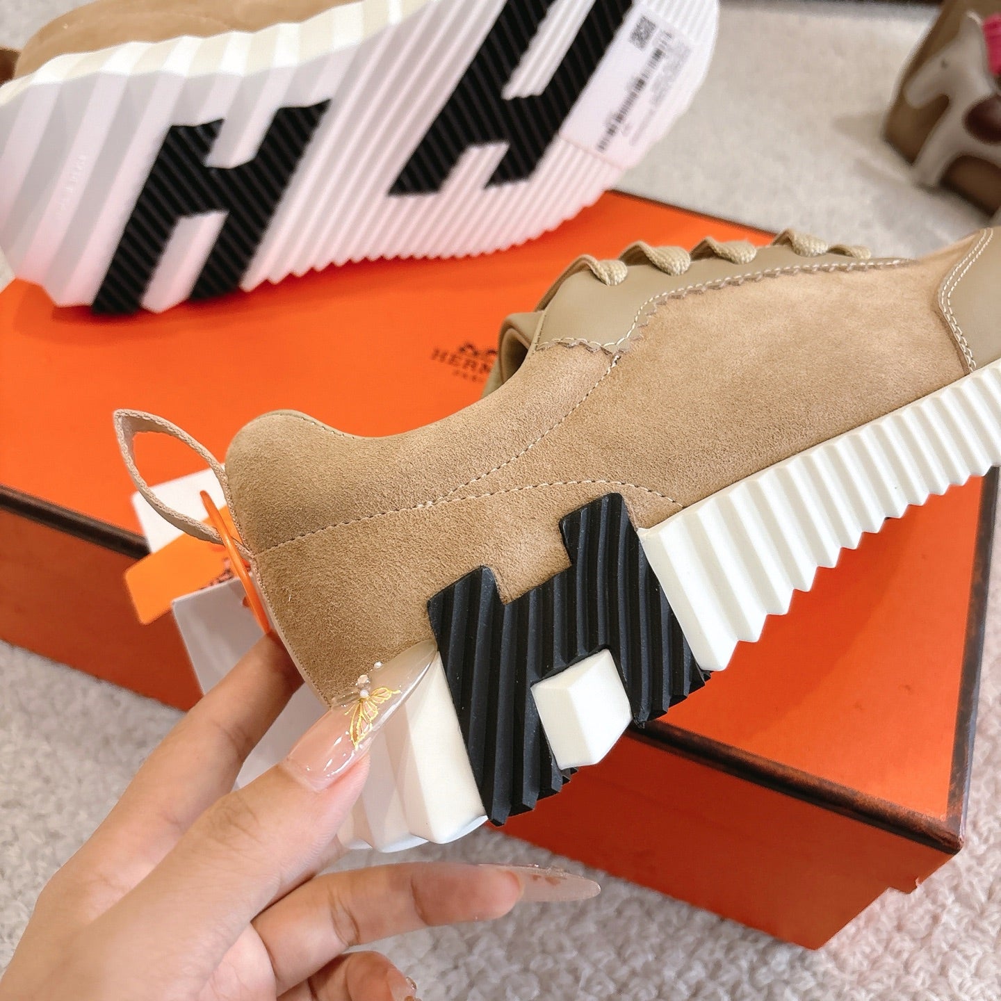 Hermes unisex sneakers outsole detail with black traction blocks and white striped midsole.