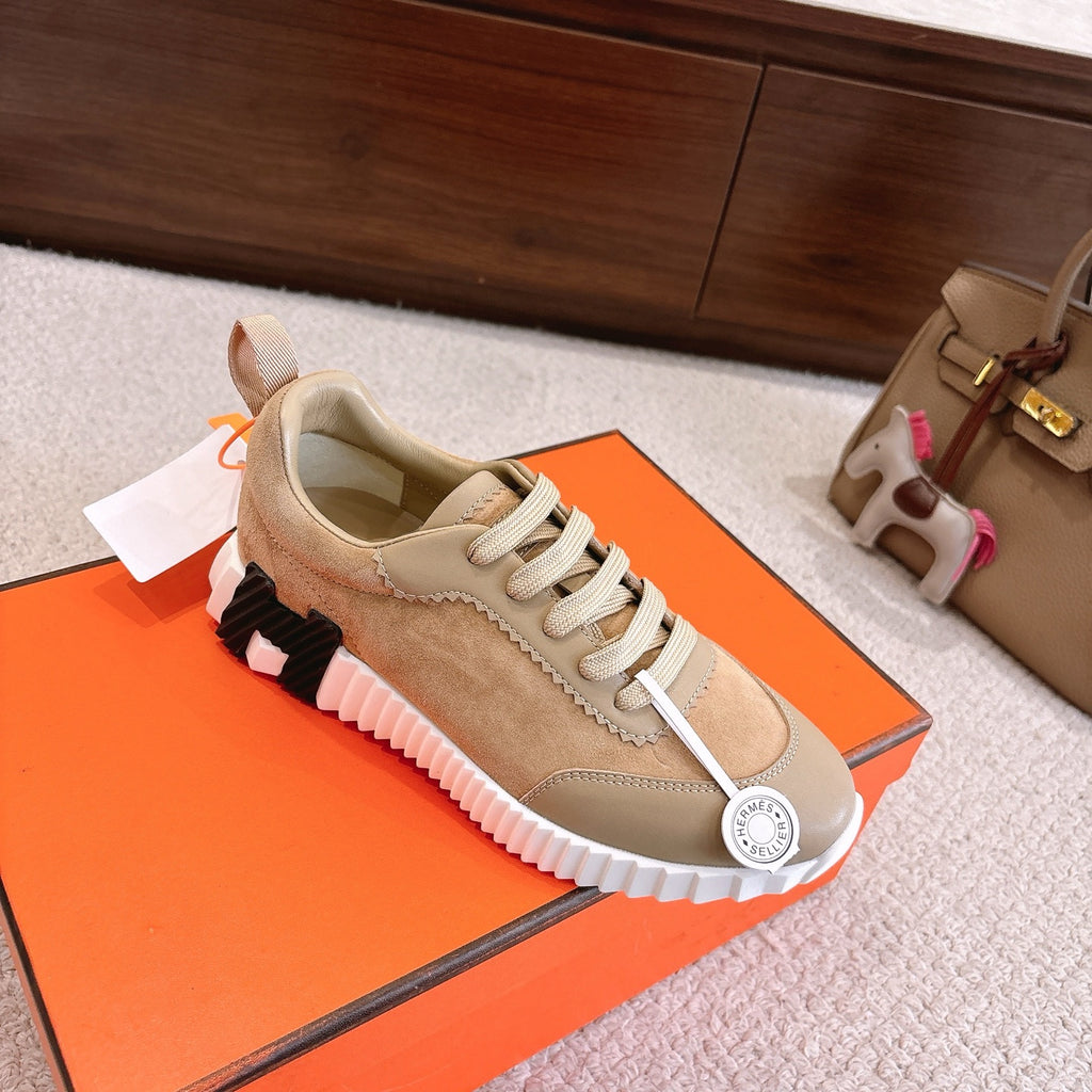 Hermes unisex sneakers with beige suede upper, cream laces, and black-and-white tread on sole.