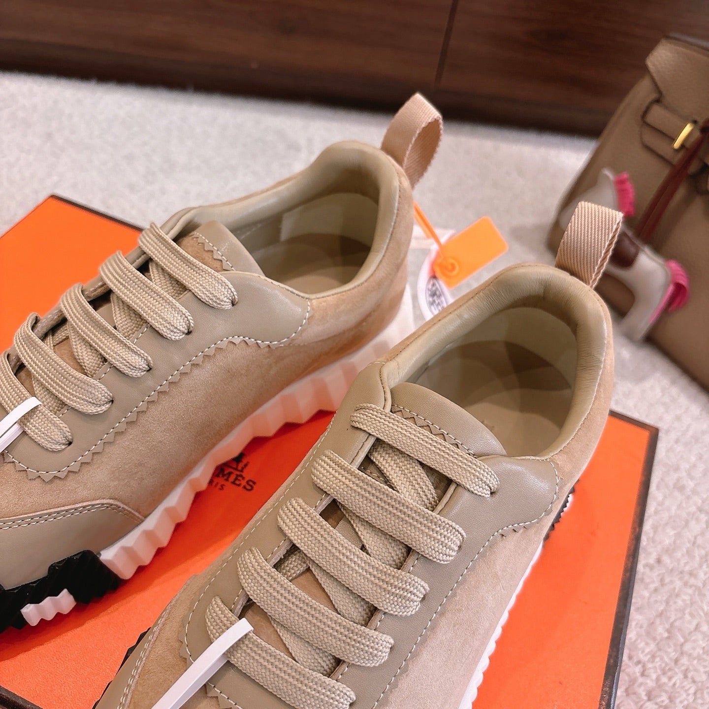 Hermes unisex sneakers pair in beige with lace-up closure and cushioned white tread soles.