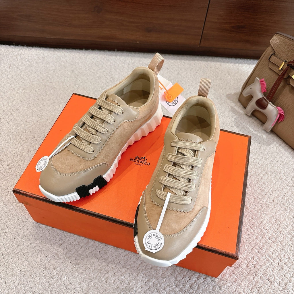 Hermes unisex sneakers on box; beige and tan uppers with lace-up design and white cushioned sole.