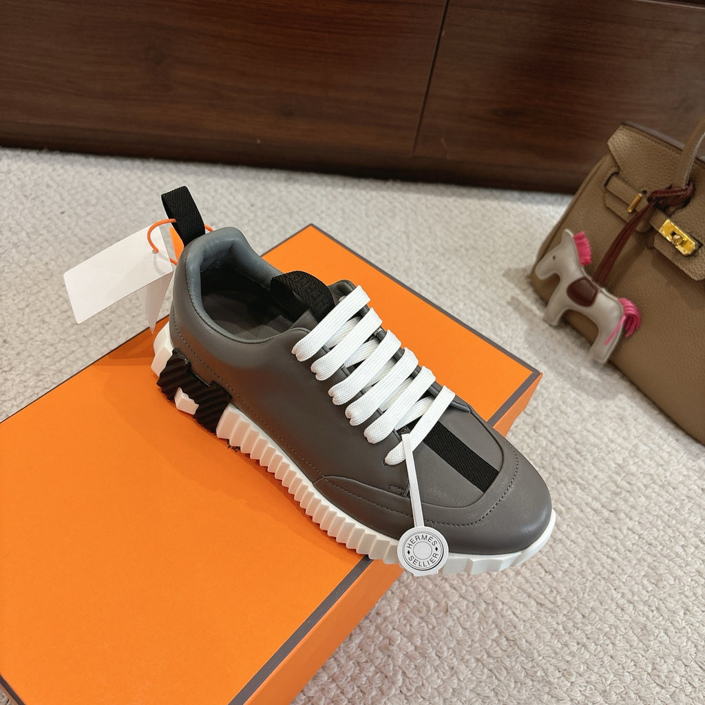 Hermes gray sneakers with white laces and black accents; white platform-style sole