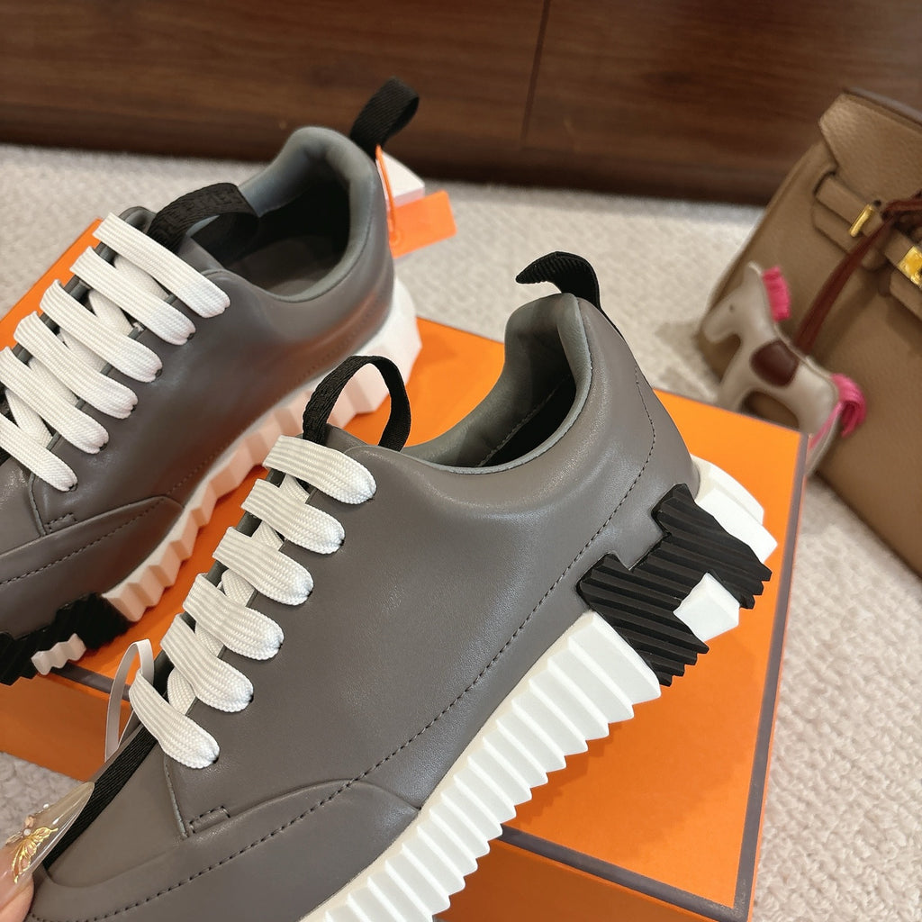 Hermes gray sneakers pair view: white laces, black side stripe, and textured tread sole