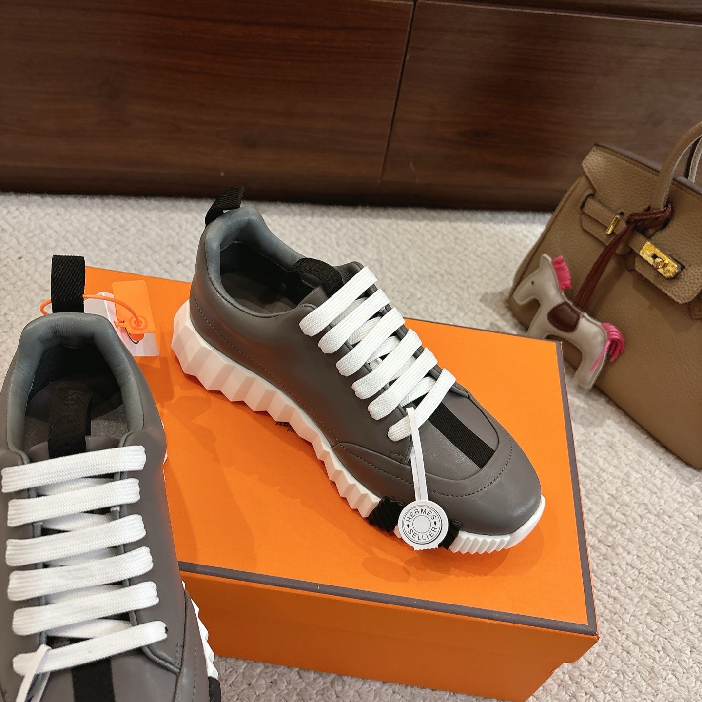 Hermes gray low-top sneakers with white laces, black heel tab, and white tread sole
