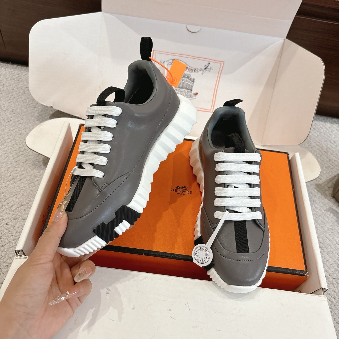 Hermes gray sneakers with white laces and black stripe detail; thick white tread sole