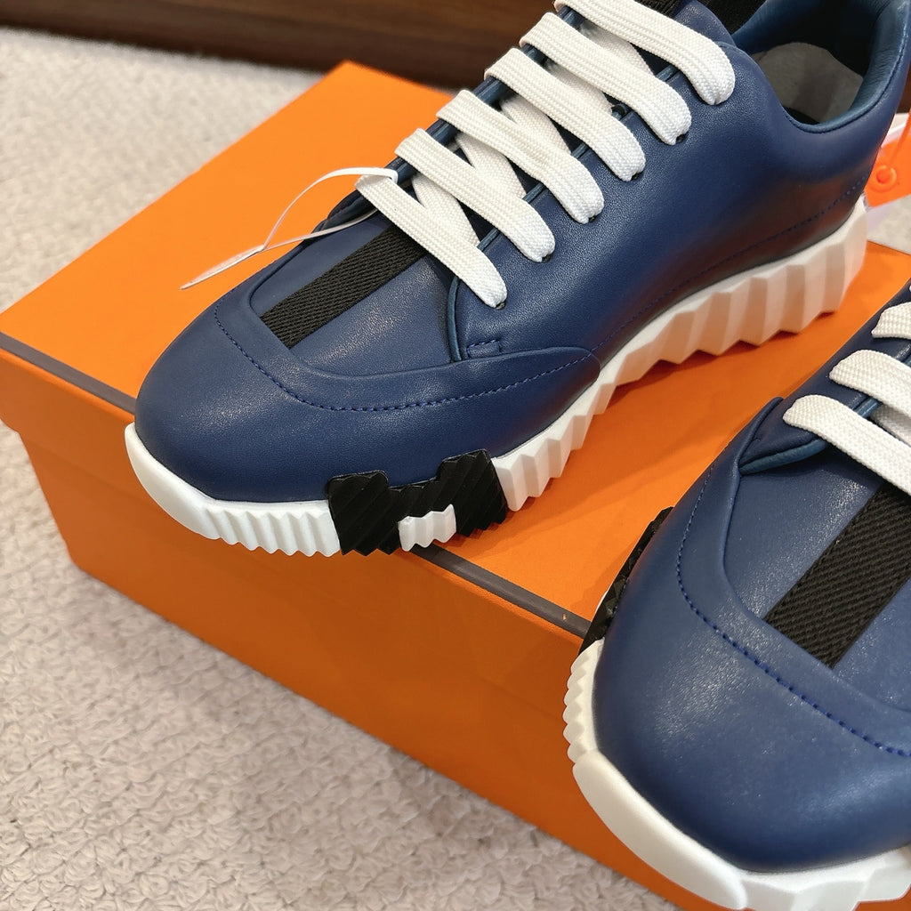 Close-up of blue sneakers with white laces, side vents, and chunky white sole