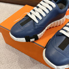 Close-up of blue sneakers with white laces, side vents, and chunky white sole