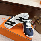 Sole view of blue sneakers with white tread, black strap detail, and lace front