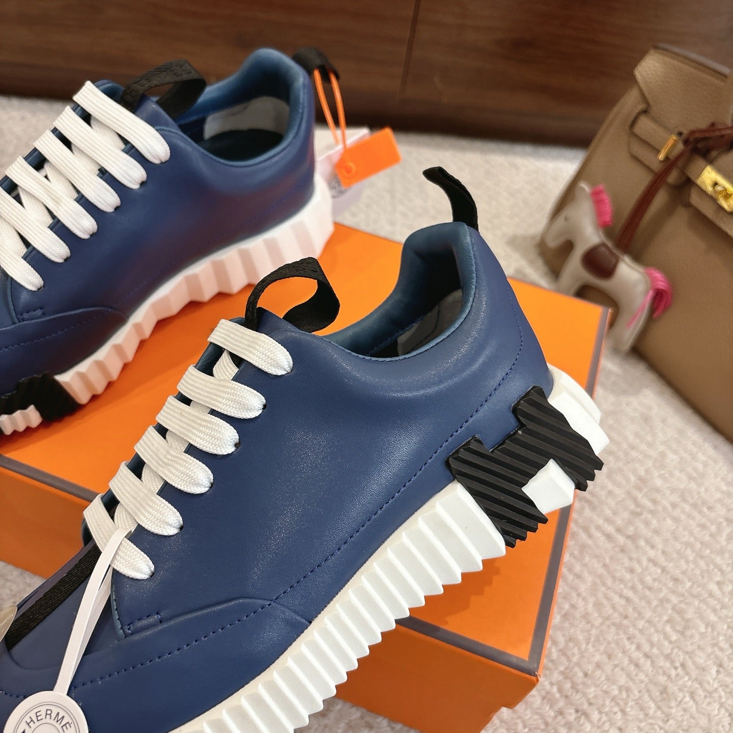 Blue sneakers with white laces and black ribbed strap detail on the side